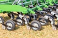 A fragment of a multi row knife harrow for field work against the background of the yellow stubble field