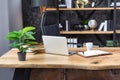 Fragment of the office. Desk with notebook, notepad, pen and plant. Nearby is a beautiful black leather armchair. In the