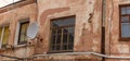 A fragment of an old building with a round satellite dish on the wall. Windos on rear facade of house. Royalty Free Stock Photo