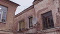 A fragment of an old building with a round satellite dish on the wall. Windos on rear facade of house Royalty Free Stock Photo