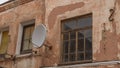 A fragment of an old building with a round satellite dish on the wall. Windos on rear facade of house Royalty Free Stock Photo