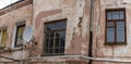 A fragment of an old building with a round satellite dish on the wall. Windos on rear facade of house. Royalty Free Stock Photo