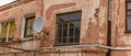 A fragment of an old building with a round satellite dish on the wall. Windos on rear facade of house. Royalty Free Stock Photo