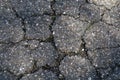 Fragment of an old cracked asphalt road with stone inclusions