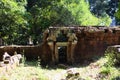 Fragment of the old dilapidated wall with a small doorway. Sunny warm day in the forest