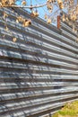 Fragment of an old fence of an abandoned construction site, made of metal sheets. Sunlit fragment of the fence Royalty Free Stock Photo