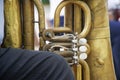 A fragment of an old musical instrument tuba, standing between the legs of a tired street musician Royalty Free Stock Photo