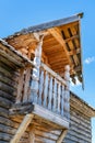 A fragment of an old Russian hut with a carved wooden balcony.