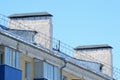 Fragment of an old slate roof with brick and metal chimneys against a blue sky Royalty Free Stock Photo