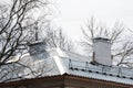 Fragment of an old slate roof with brick and metal chimneys against a blue sky Royalty Free Stock Photo