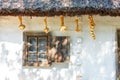 A fragment of an old Ukrainian rural hut with an old window with wooden shutters under a thatched roof Royalty Free Stock Photo