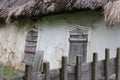 Fragment of old Ukrainian traditional house with straw roof, white clay walls and wooden windows Royalty Free Stock Photo