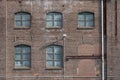 A fragment of an old and weathered facade of an old factory, made of masonry, steel and wooden frames