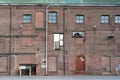 A fragment of an old and weathered facade of an old factory, made of masonry, steel and wooden frames