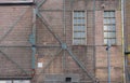 A fragment of an old and weathered facade of an old factory, made of masonry, steel and wooden frames