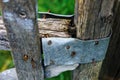 Fragment of an old wooden fence with metal attachment, close-up. Dilapidated village fence with rusty nails