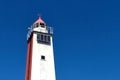 Fragment of an old wooden lighthouse against a blue sky, solar panels mounted on the wall