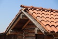 Fragment of old, worn brown tile roof on the right of house