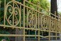 A fragment of an old yellow iron fence with a wrought pattern in the park Royalty Free Stock Photo