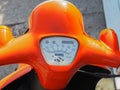 Motorcycle speedometer located on the orange steering wheel shining in the sun.