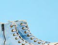 Fragment of a pair of light blue worn textile sneakers with laces and zippers