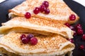 Fragment of a pile of pancakes on a black plate with red berries Royalty Free Stock Photo