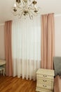 fragment of pink bedroom with curtain, tulle, bed, pillow and nightstand closeup photo