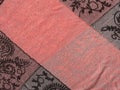 Fragment pink scarf with black patterns on a gray background. Diagonal location