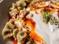 Fragment of plate of traditional Turkish food. Turkish Manti with red pepper, tomato sauce, yogurt and mint. Top view