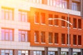 Fragment of a red-gray ventilated facade with windows in the sun. In the foreground is a modern street lamp Royalty Free Stock Photo