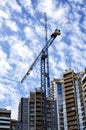 A fragment of a residential building under construction and high-rise cranes against a bright cloudy sky Royalty Free Stock Photo