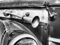 Fragment of a retro car with a signaling beep outside and splattered with dirt. Black and white photo