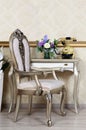 A fragment of a retro interior with a chair and a desk on which is located a telephone and a vase of flowers Royalty Free Stock Photo