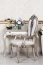 A fragment of a retro interior with a chair and a desk on which is located a telephone and a vase of flowers Royalty Free Stock Photo