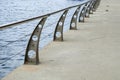 Fragment of river embankment with concrete pavement, modern metal balustrade with steel handrails Royalty Free Stock Photo