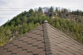 Fragment of the roof covered with flexible shingles in the form of honeycomb on the background of the mountain