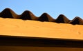 A fragment of the roof of a rural house with siding and a new wooden Board against the blue sky Royalty Free Stock Photo