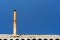 Fragment of roof of village house covered with slate with tall old rusty iron chimney on clear blue sky in sunlight closeup Royalty Free Stock Photo