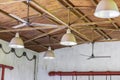 A fragment of a room with gas pipes on the walls and identical lamps and fans on the wooden ceiling. Interior design in