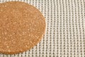 A fragment of a round beige cork coaster on a rough knitted tablecloth. Food menu template