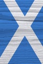 Fragment of Scottish flag on a dry wooden surface. Natural vertical background, wallpaper or backdrop made of old wood. Rough