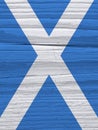 Fragment of Scottish flag on a dry wooden surface. Natural vertical background, wallpaper or backdrop made of old wood. Rough