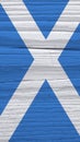 Fragment of Scottish flag on a dry wooden surface. Vertical mobile phone wallpaper. Natural background made of old wood with the