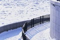 A fragment of the snow-covered granite embankment of the Amur River. Pieces of ice floes under the snow. Striped shadows