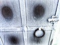 Fragment of snow covered metal forged lattice on the door. Square iron rivets on the door grill in winter. Background Royalty Free Stock Photo