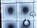 Fragment of snow covered metal forged lattice on the door. Square iron rivets on the door grill in winter. Background Royalty Free Stock Photo