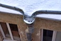 Fragment of the snow-covered roof of an old house with a drain with frozen water Royalty Free Stock Photo