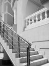 A fragment of a staircase with modern railings leading to a building with columns and vintage railings