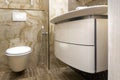 Fragment of a toilet with a natural stone finish. Interior design of a bathroom in yellow and white