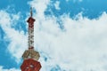 A fragment of a TV tower against a blue cloudy sky on a sunny day. Bottom view. Royalty Free Stock Photo